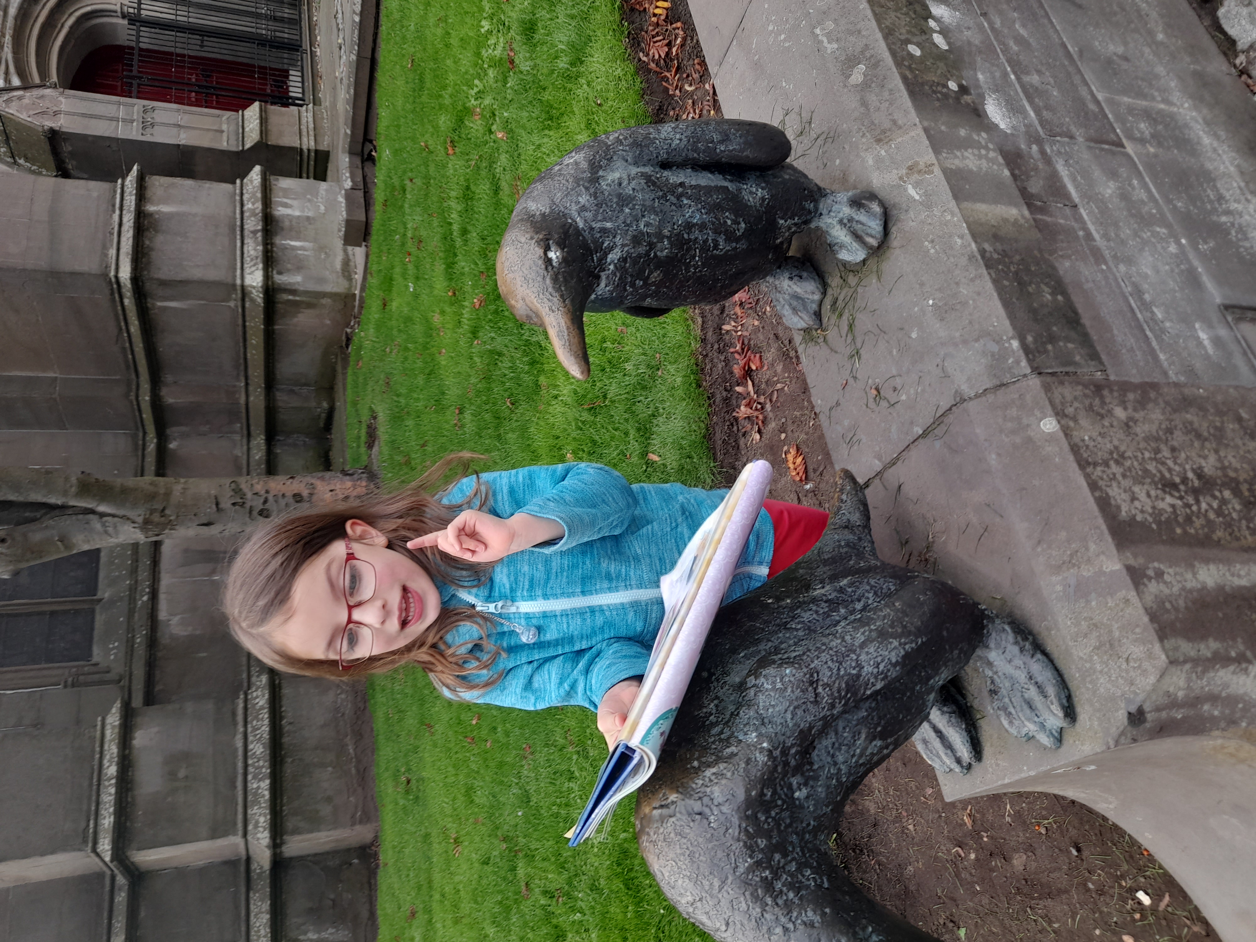 my daughter reading books to penguin statues